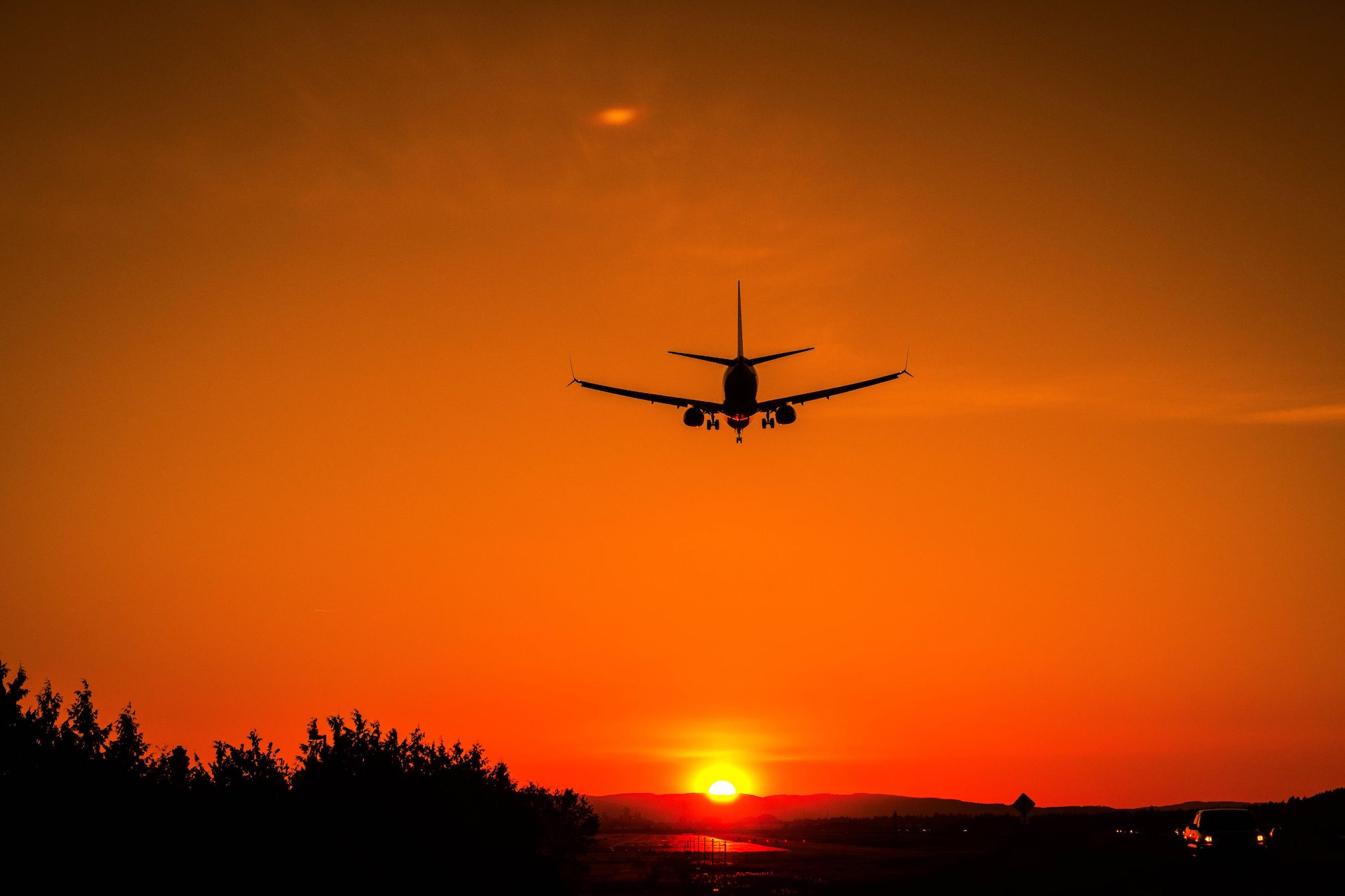 An airline jet seen from behind flying into the sunset